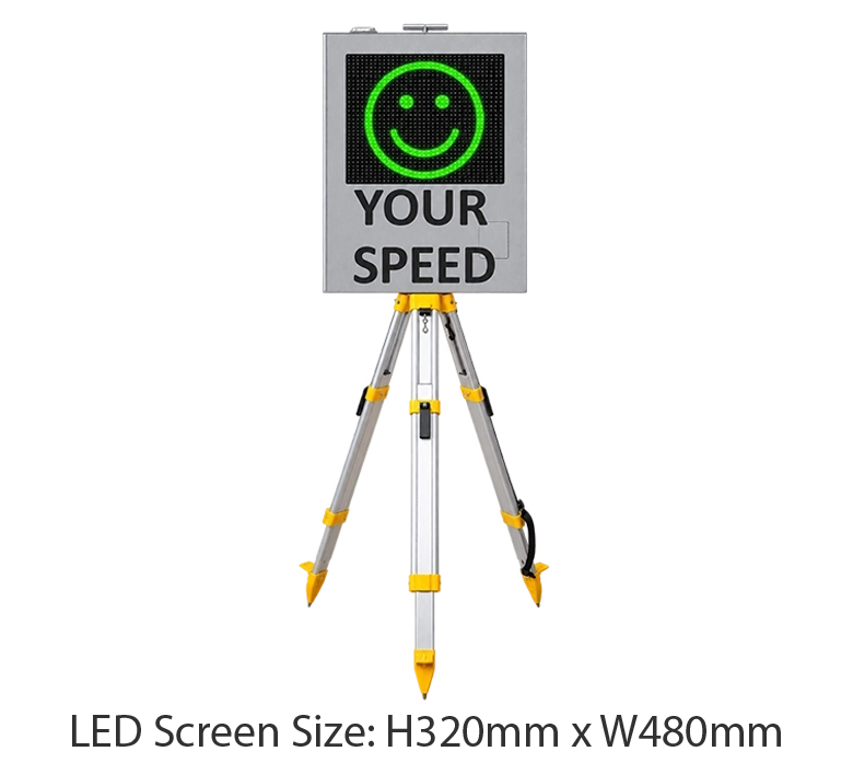 Tripod Mounted Radar Speed Sign 1 Tripod-mounted radar speed sign displaying a green smiling face above “Your Speed” beside trucks at a freight depot.